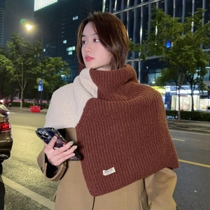 Detail of two-tone knit shawl showing beige and brown textures and a woven brand label