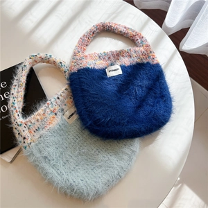 Detail of colorful knitted mohair tote bags with brand label on a minimalist white table