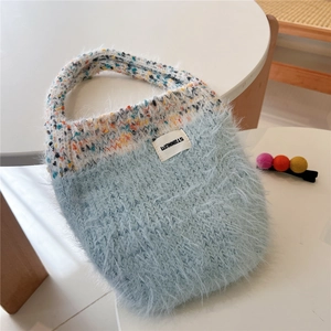 Detailed texture of light blue plush knit handbag with colorful woven handles and white label