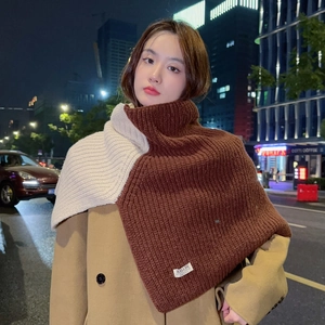 Close-up of dual-color ribbed knit high-neck shawl with brand logo tag detail