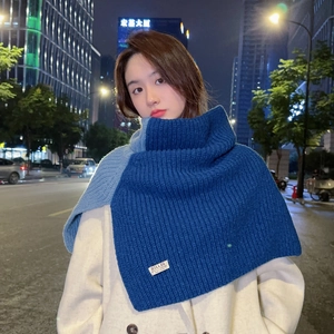 Close-up of dual-tone blue knitted turtleneck shawl with a detailed woven brand label