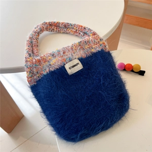 Detail of royal blue plush tote bag with colorful knitted handle and Stannum label