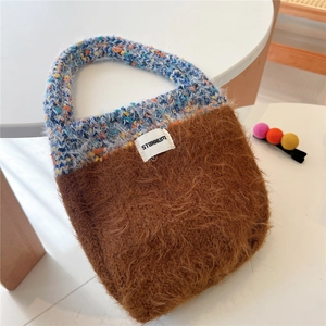Detail of plush brown tote bag with colorful knit handle and Stannum label on table