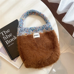 Close-up of knit and plush patchwork handbag with STANNUM brand label on a table