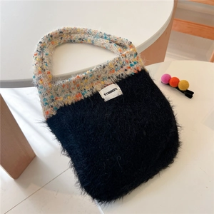 Close-up of contrast knit and black faux fur handbag with white STANNUM logo label