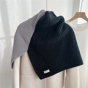Detail of chunky ribbed knit neck warmer featuring a brand label and autumn texture