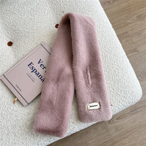 Détail de l'écharpe rose en fausse fourrure avec logo sur fond en polaire blanche douce