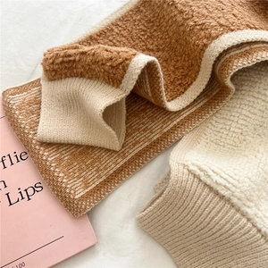 Detail von weichem braunem Teddy-Fleece und cremeweißer Rippstrick-Struktur am Halswärmer