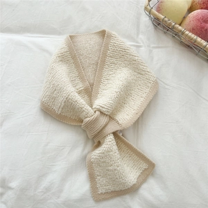 Detail eines cremefarbenen Strickschals mit strukturierter Wolle und Rippbündchen