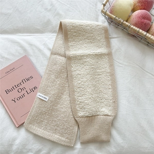 Nahaufnahme des weichen, beigen Strickschals mit Rippenrand und Herkunftsetikett