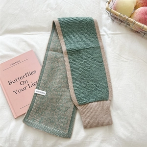Detailaufnahme von grünem und beigeem Strickschal mit weicher Textur und Rippstrick
