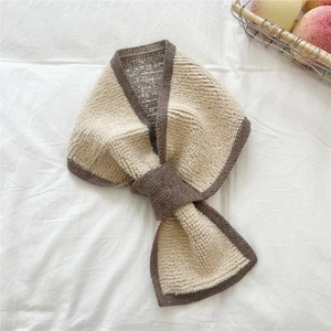 Detail des gekreuzten Strickschals in Beige und Braun mit warmer, strukturierter Strickoberfläche