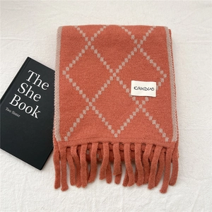 Close-up of orange diamond pattern knit scarf featuring fringe tassels and brand label