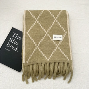 Detail of green argyle knit scarf with white grid pattern and elegant fringed edges
