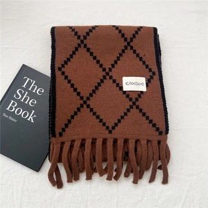 Close-up of brown and black argyle knit scarf with fringe trim and brand label detail