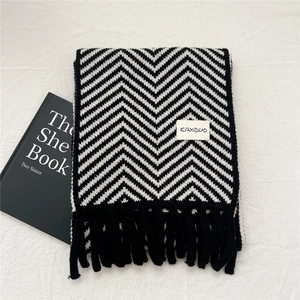 Detail of black and white herringbone knit scarf with soft fringe and logo patch