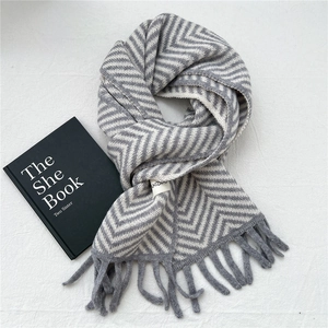Detail of grey and white herringbone knit scarf with soft fringe and stylish brand tag