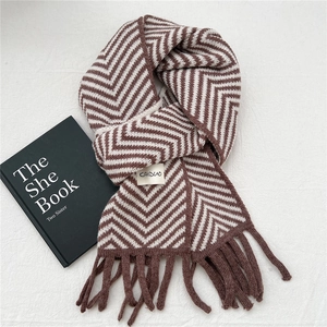 Detail of chevron pattern knit scarf with tassel trim and a minimalist woven label