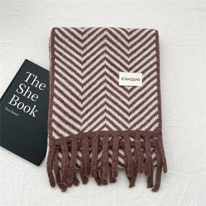Close-up of thick knitted winter scarf with brown and white zigzag pattern and fringe detail