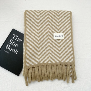 Detail of khaki wavy knit scarf texture with soft fringe and minimalist woven label