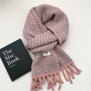 Detail view of pink and grey chevron knit scarf with soft fringe and logo label