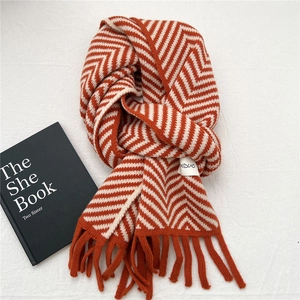 Macro detail of the orange and white wavy knit scarf with soft fringe and logo label