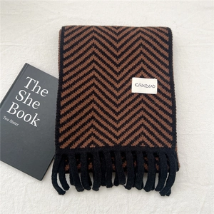 Detail of knit scarf with black and brown zigzag patterns and elegant fringe tassels