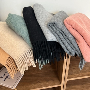Long wool scarf with tassels in various autumn colors stacked on a wooden shelf