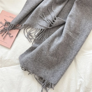 Detail of dark grey wool scarf with soft fringed edges and warm knitted texture