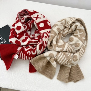 Dettaglio di sciarpe in maglia rossa e kaki con motivi a cuore e texture morbide