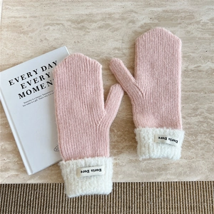 Detail of pink knitted mittens with white faux fur cuffs and a decorative label