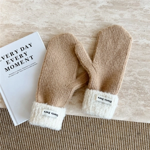 Detail of camel knit mittens with white plush cuffs and Doria Dore woven label