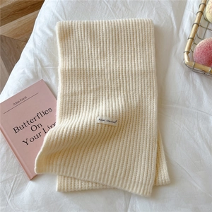 Close-up of off-white knitted scarf with thick vertical stripes and brand label