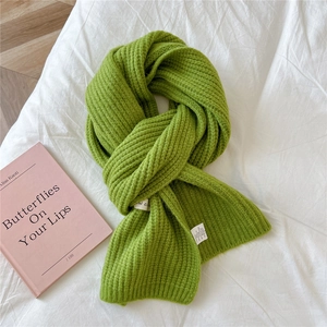 Close-up of bright green chunky knit scarf with vertical stripes on white fabric