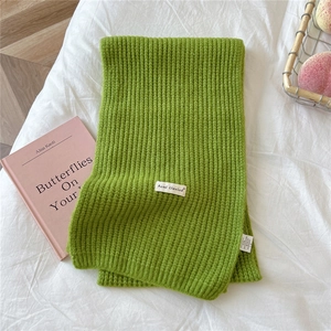 Detail of ribbed knit green scarf showing the soft texture and detailed washing label