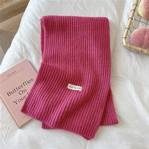 Detailed texture of rose pink knitted scarf with ribbed pattern and brand label