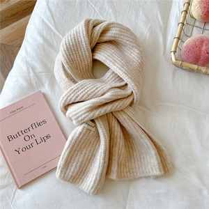 Close-up of thick knitted winter scarf with ribbed texture and decorative fabric label