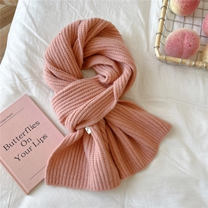 Detail of pink knitted rib scarf with woven label on a cozy white aesthetic background