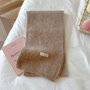 Detail of brown chunky knit scarf with vertical stripes and woven brand label
