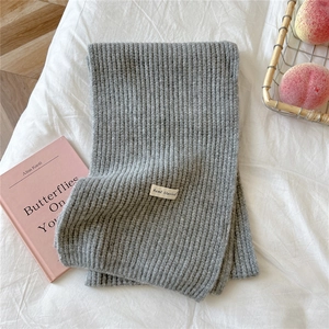 Detail of gray knitted scarf showing ribbed texture and minimalist woven label