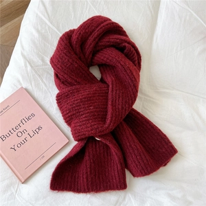 Close-up of chunky burgundy knit scarf texture with soft warm wool yarn on white fabric
