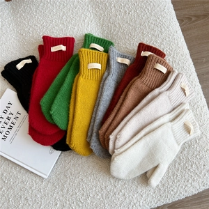 Detailed view of colorful 100% wool knitted mittens in various winter hues and soft texture