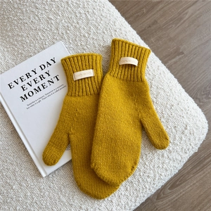 Detail of yellow wool knit mittens with 100% wool label and ribbed wrist cuffs