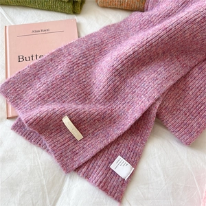 Detailed view of the wool blend knit texture and brand tag on a warm purple scarf