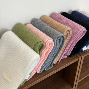 Detail showing various colors of soft ribbed knit scarves neatly arranged on wood