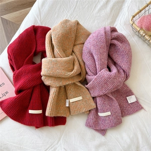 Close-up of thick knit scarves in red, orange and purple with soft ribbed texture