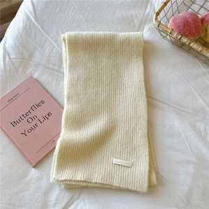 Close-up of soft ribbed knit scarf in cream white with a woven DORIA DORE fabric label
