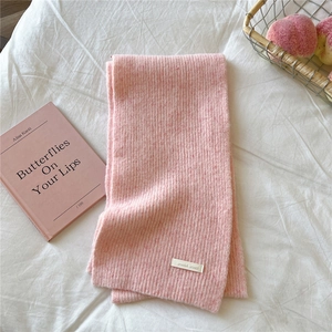Detail of pink knitted scarf with ribbed texture and white woven brand label