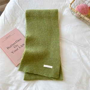 Close-up of grass green knit scarf with ribbed texture and DORIA DORE brand label