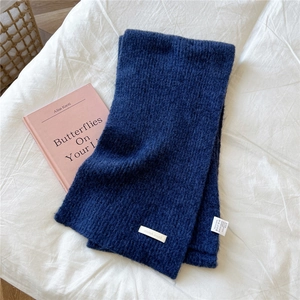 Detail of navy knit scarf showing ribbed texture and white decorative brand label
